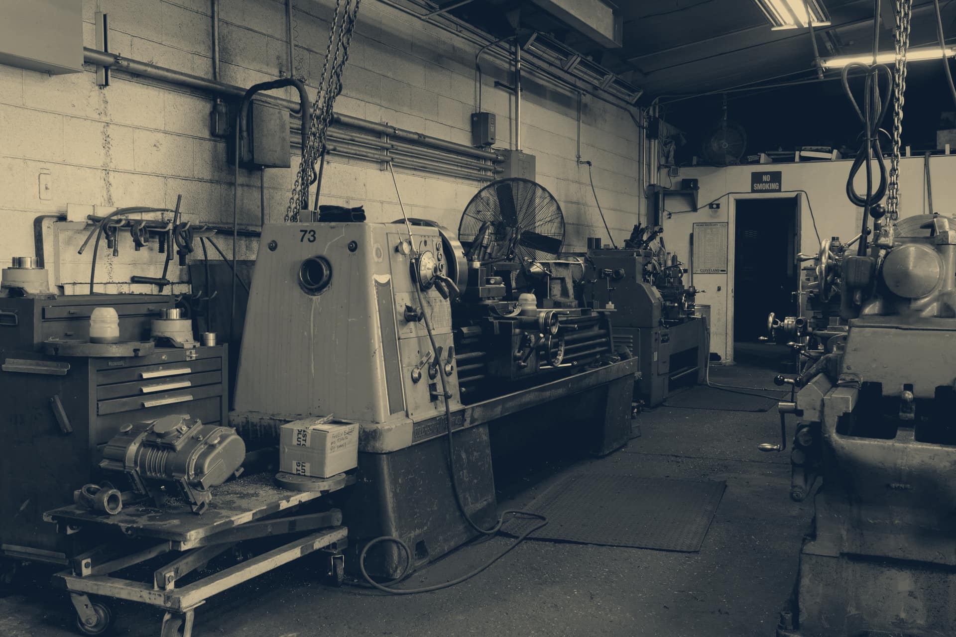 Atelier d'usinage, tours et machines alignés le long d'une allée.